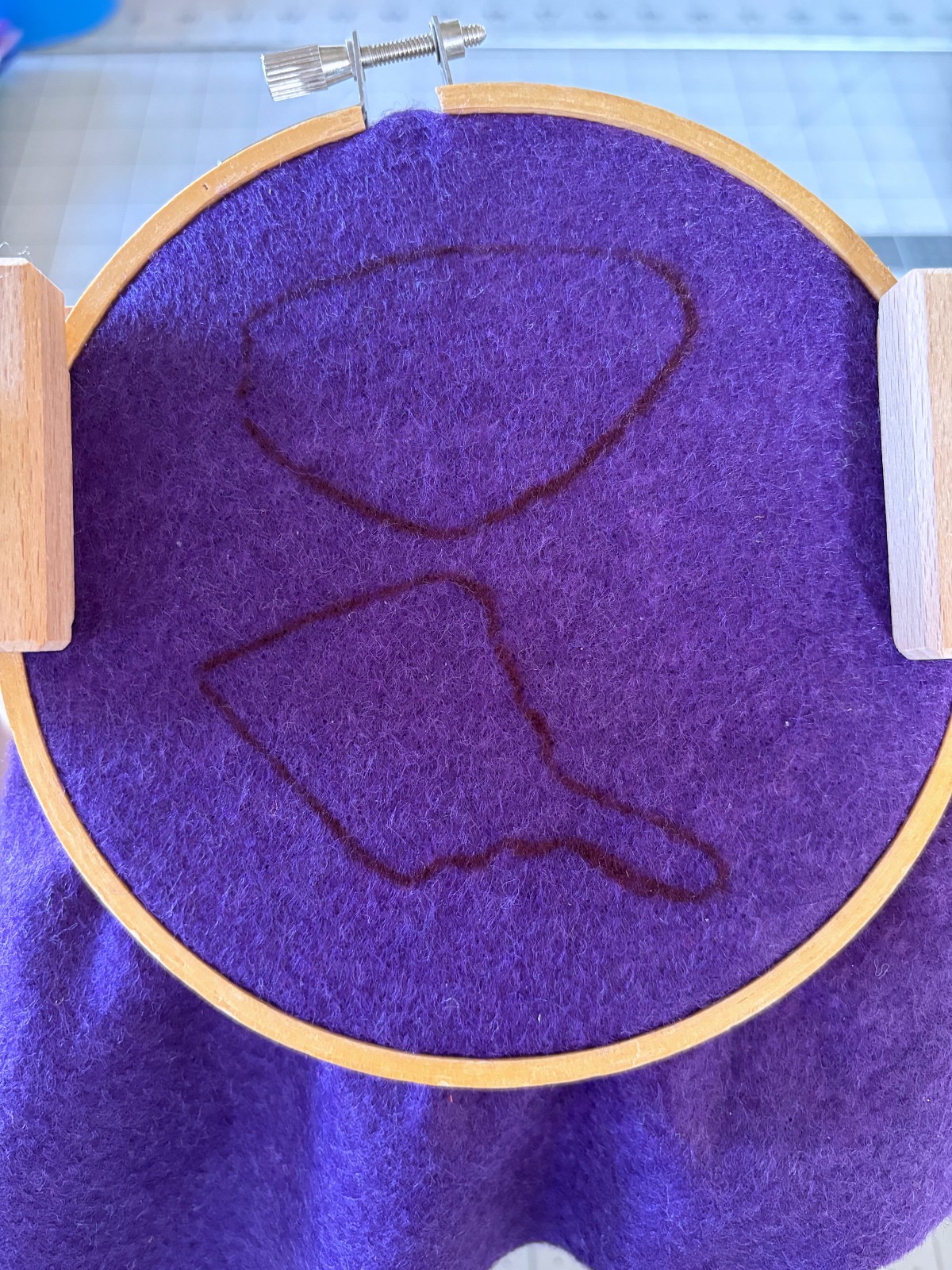 Right wing pattern traced on purple felt in an embroidery hoop.