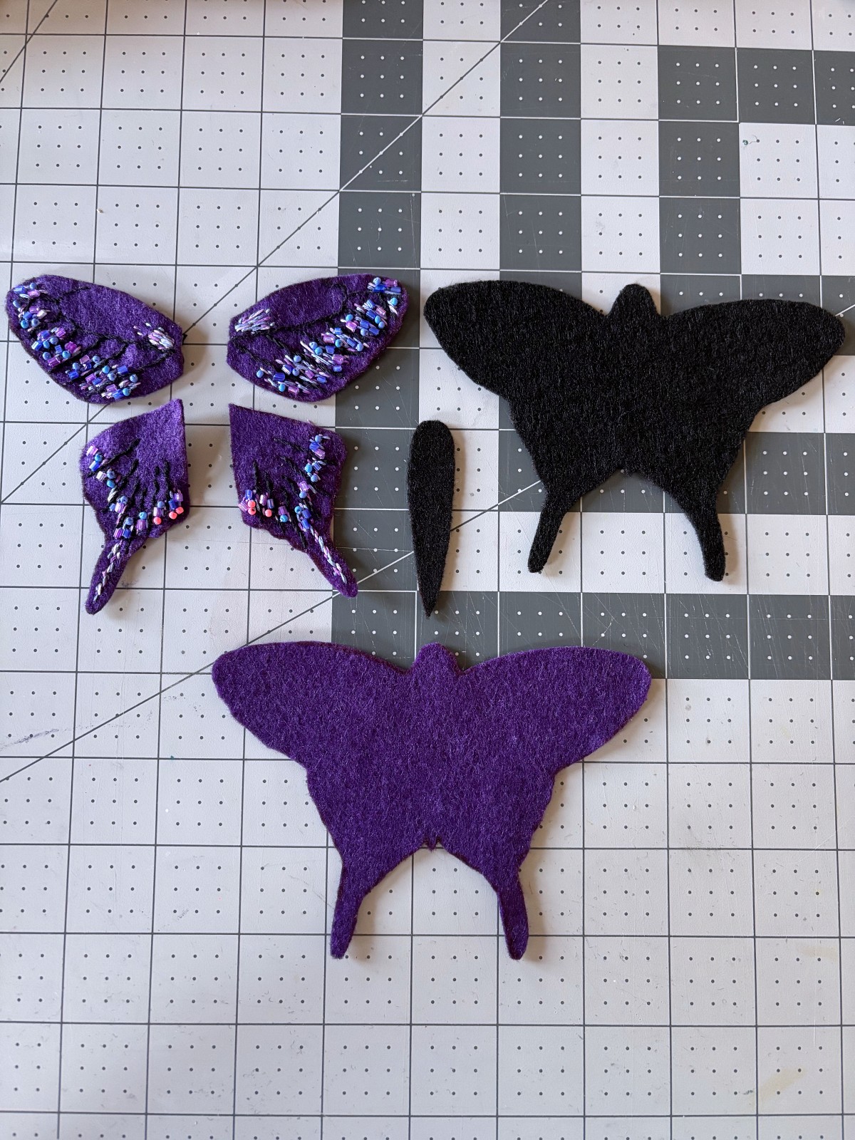 All purple butterfly ornament pattern pieces cut out of felt, on a table.