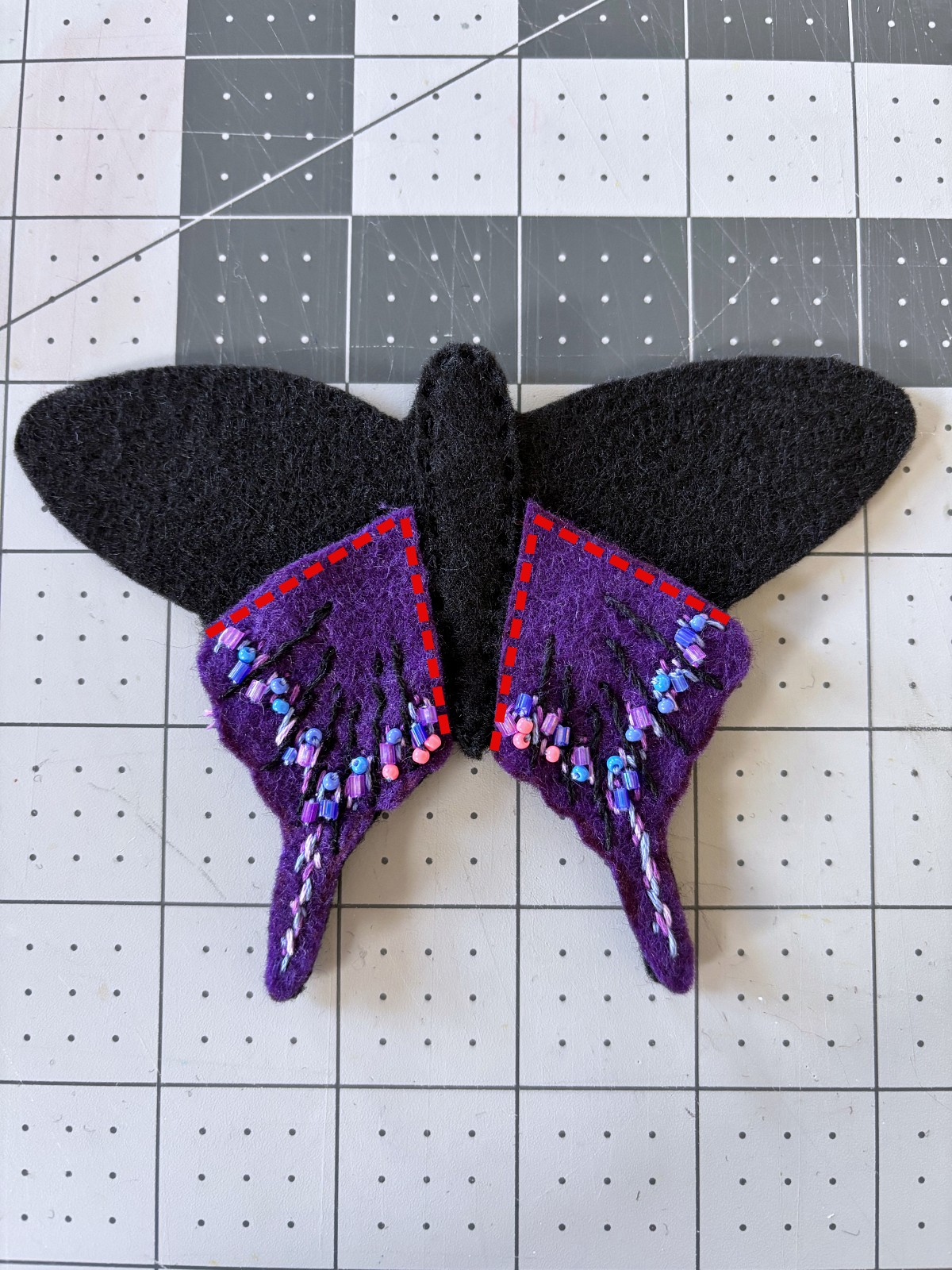 Both bottom butterfly wings arranged on base piece with red lines indicating where to sew.