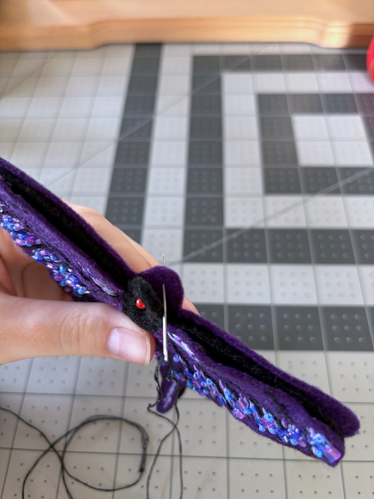 Sewing a blanket stitch around the purple butterfly ornament, starting in-between the two base layers.