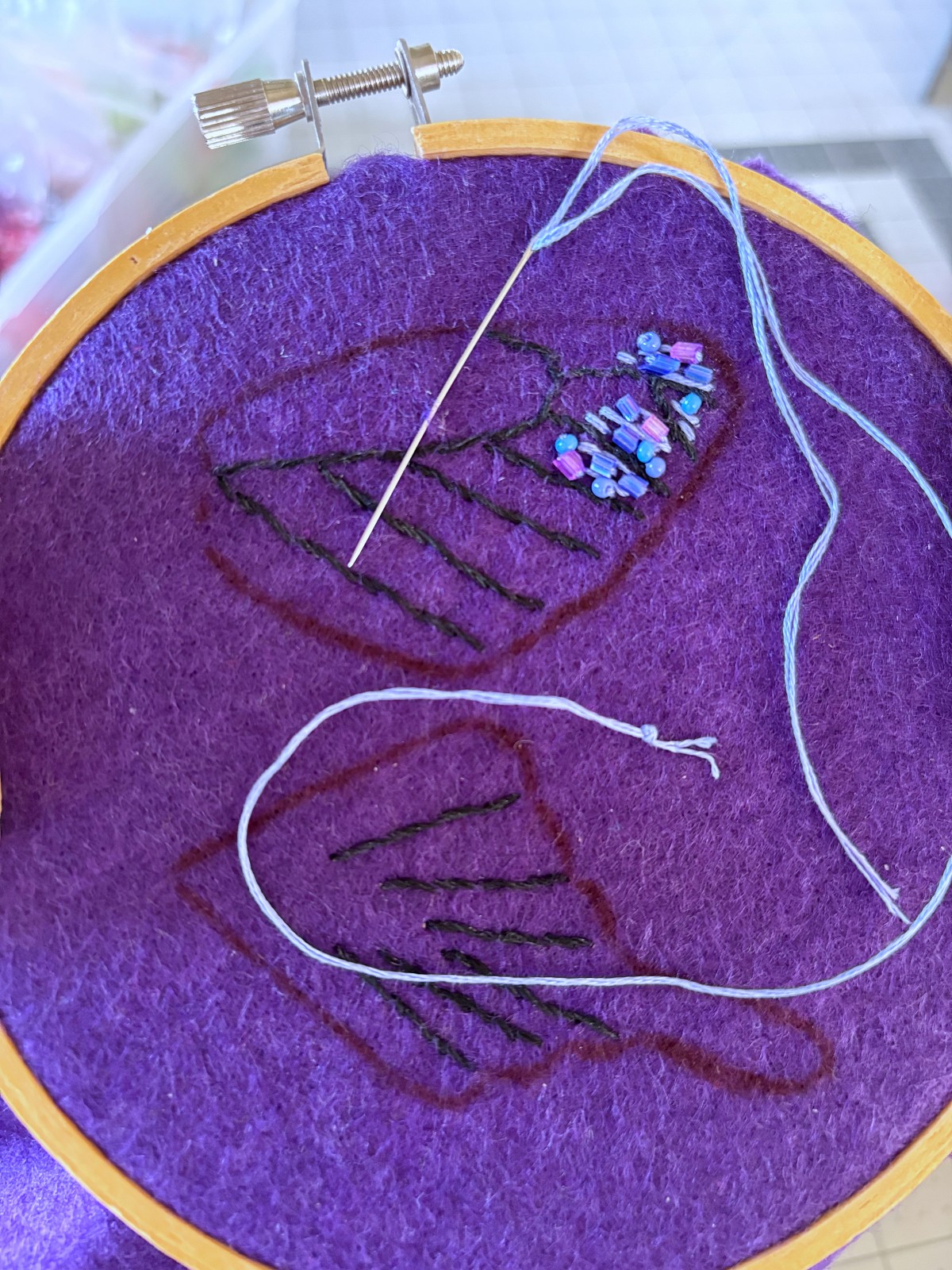 Purple beads and embroidery thread sewn onto wings.