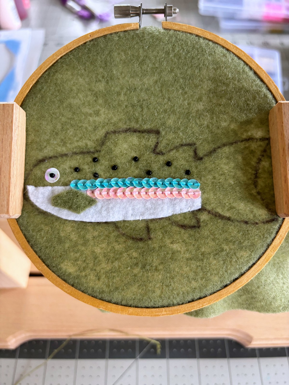 Black seed beads sewn on the body of the rainbow trout ornament.