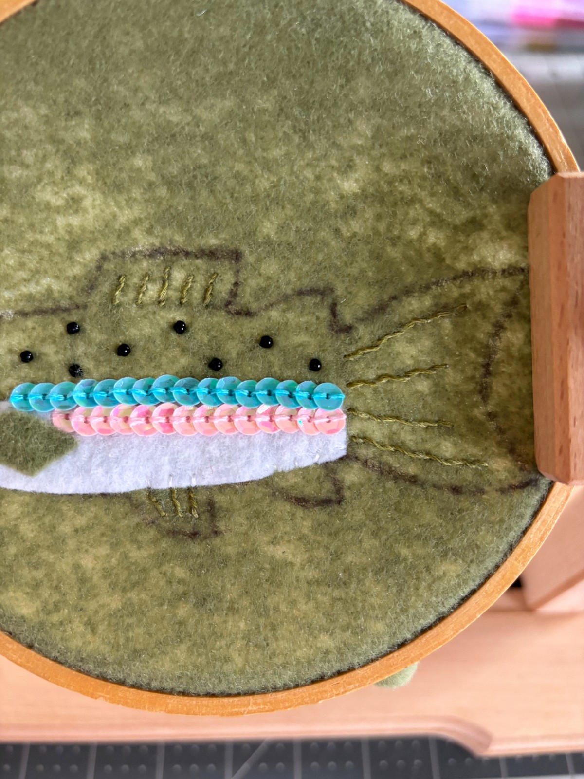 Embroidery details on the fins of the rainbow trout ornament.