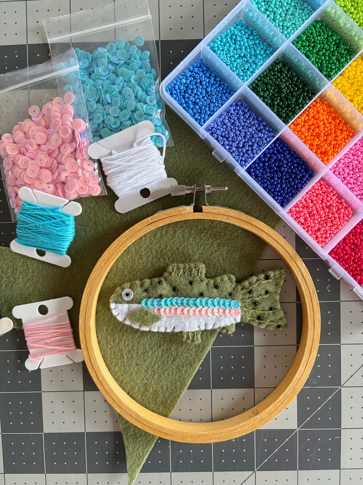 Finished rainbow trout ornament surrounded by craft supplies.