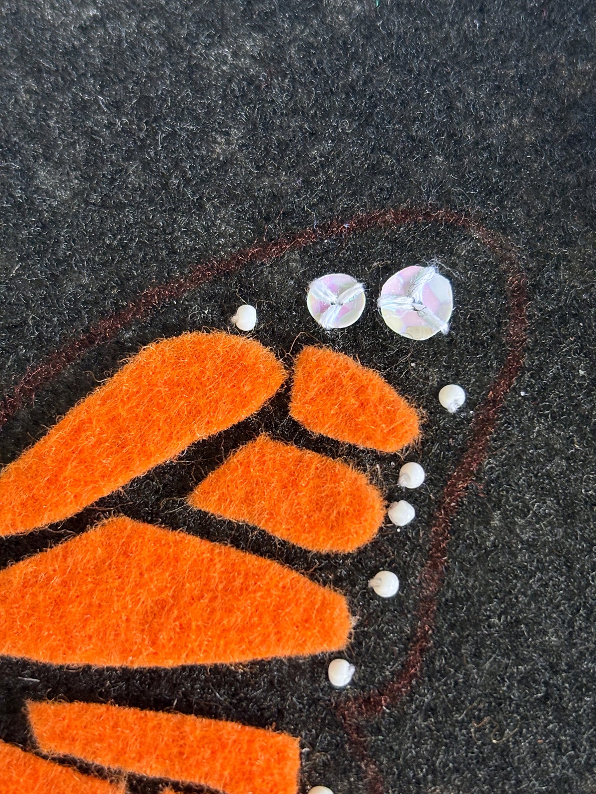Up close of the white sequin and bead details on the butterfly wing.