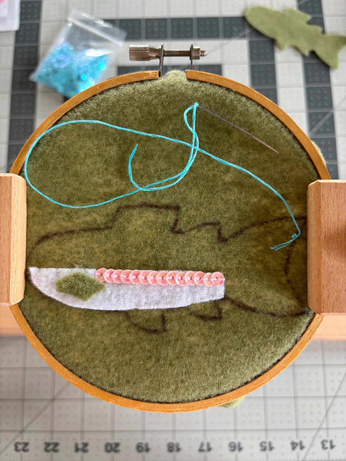 Sewn pink sequin line on the white belly of the rainbow trout body.