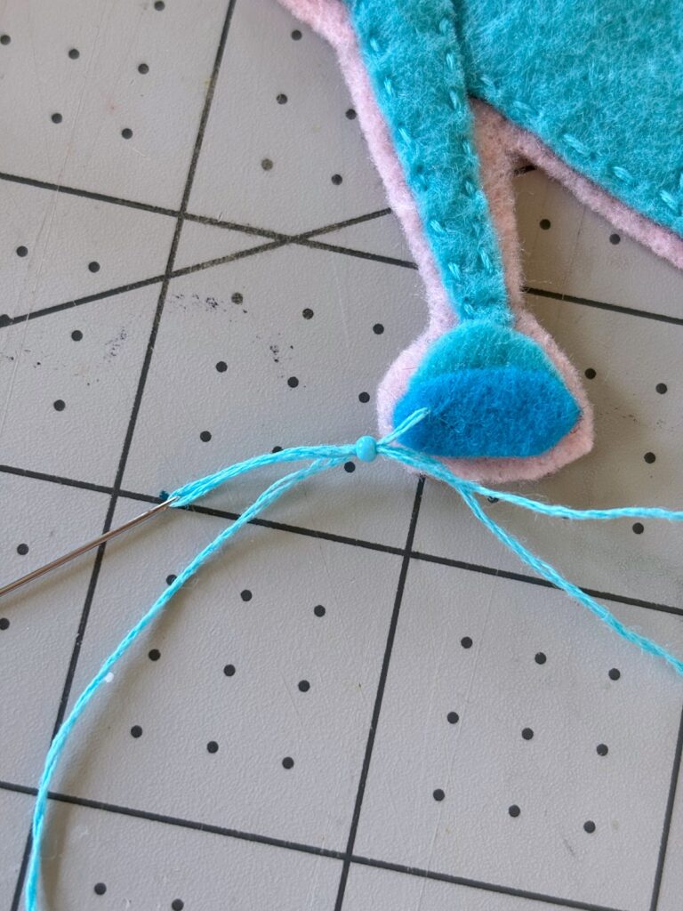 Sewing one seed bead onto embroidery thread.