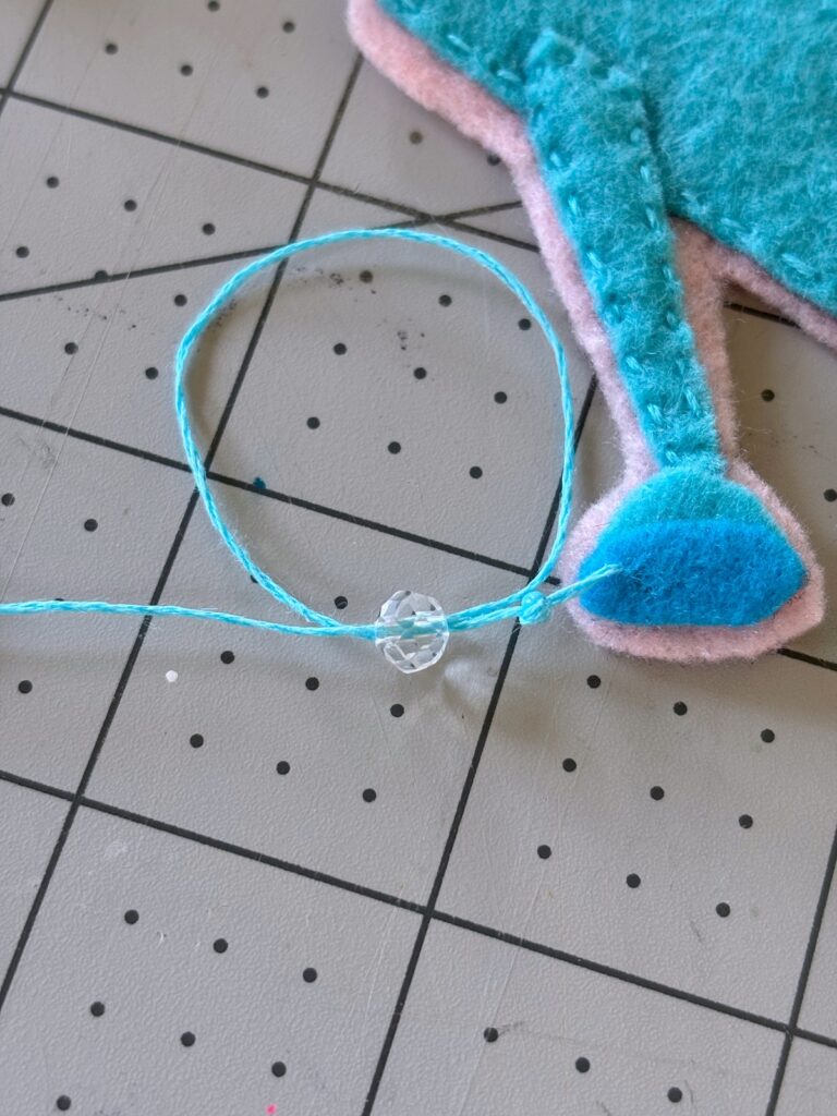 Sewing a sun catcher bead onto embroidery thread.