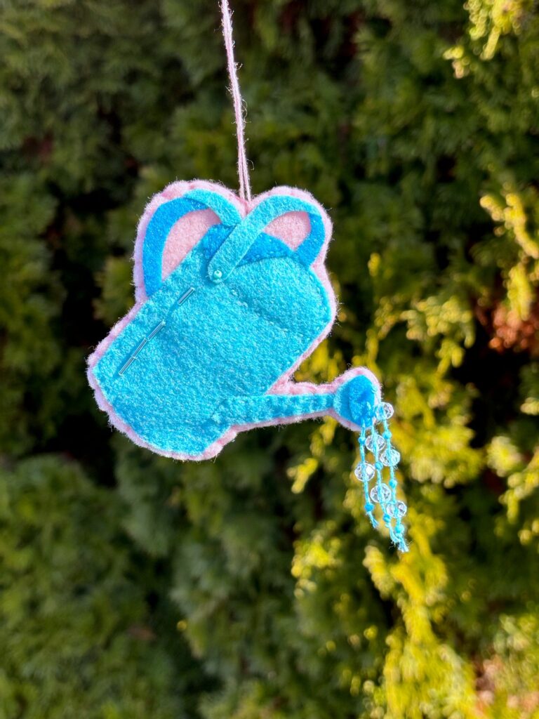 Hanging watering can ornament outside.