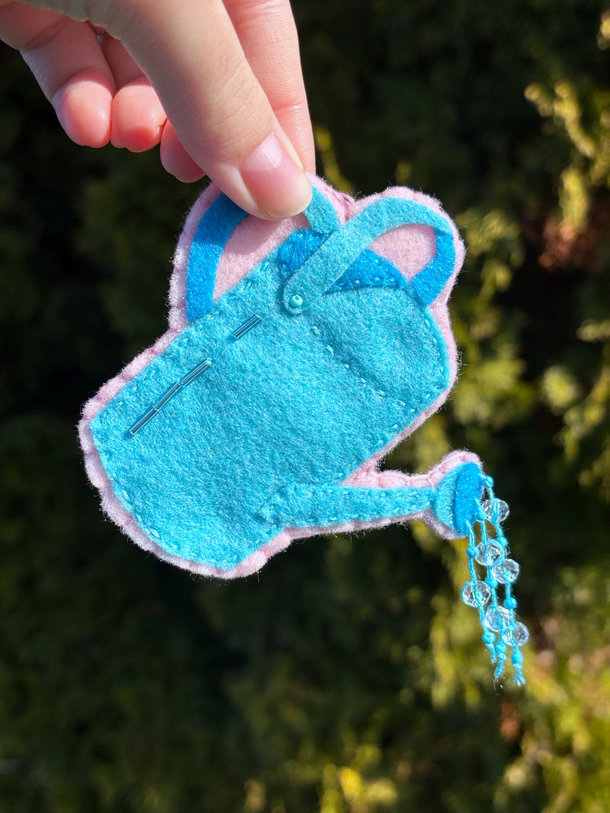 Hand holding finished watering can ornament.