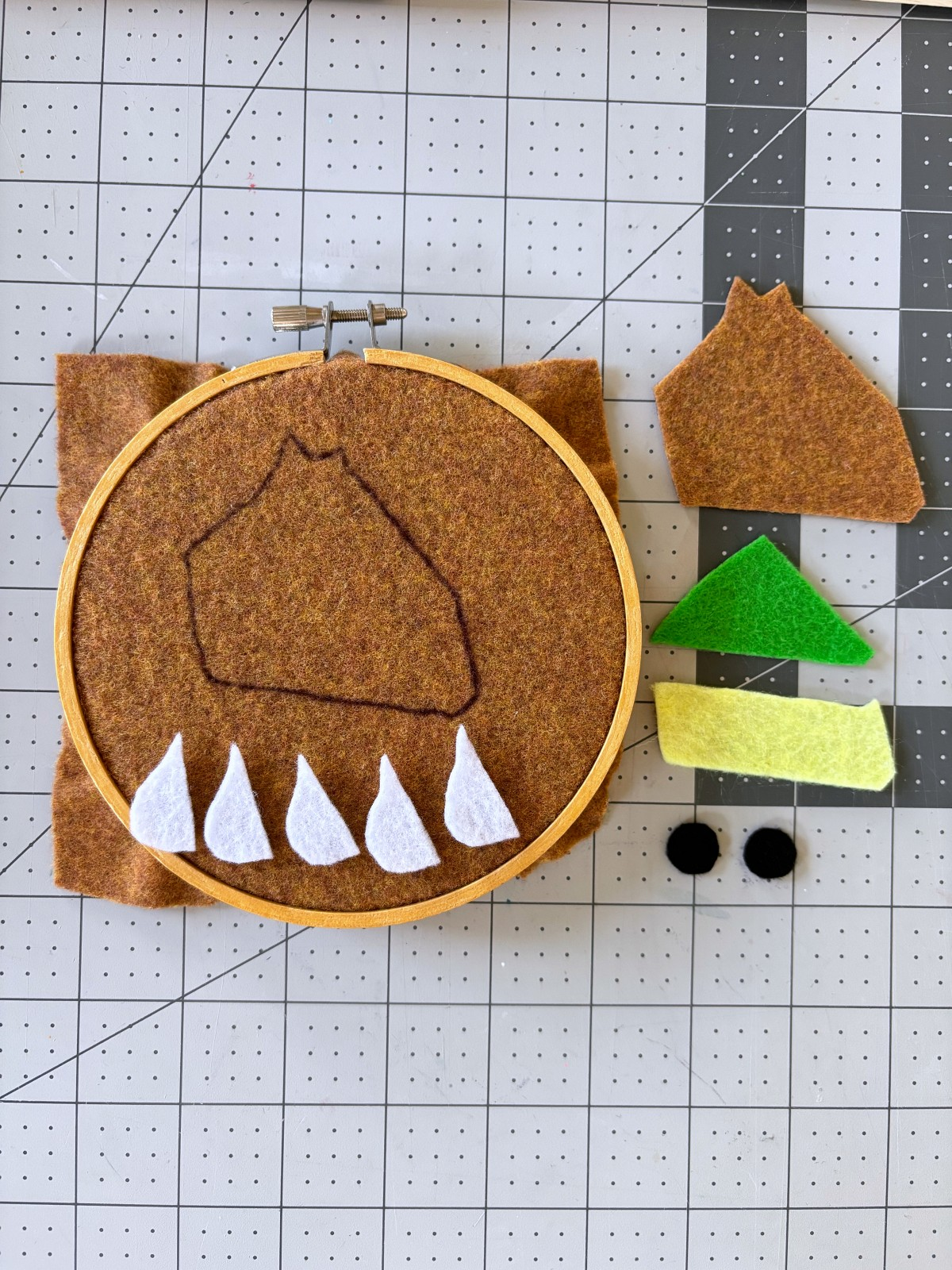 Felt in an embroidery hoop on a table with cut out pattern pieces. 