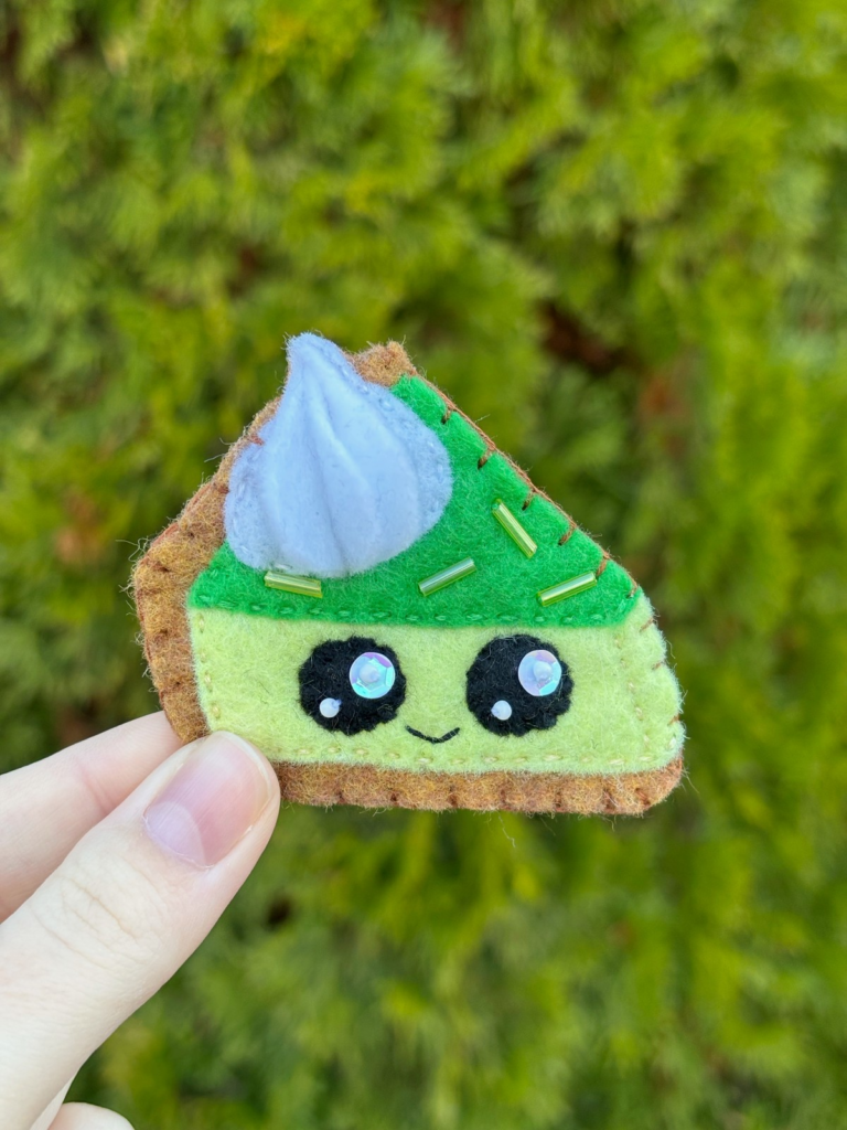 Hand holding pie ornament outside.