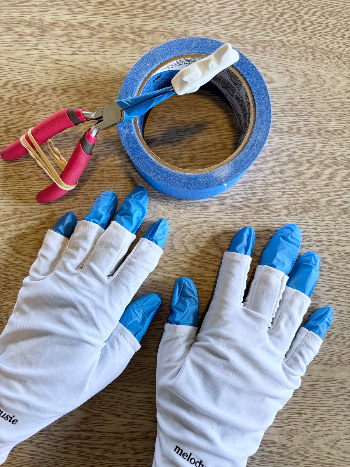 Pliers with painters tape and both safety gloves I wear while I UV resin polymer clay.