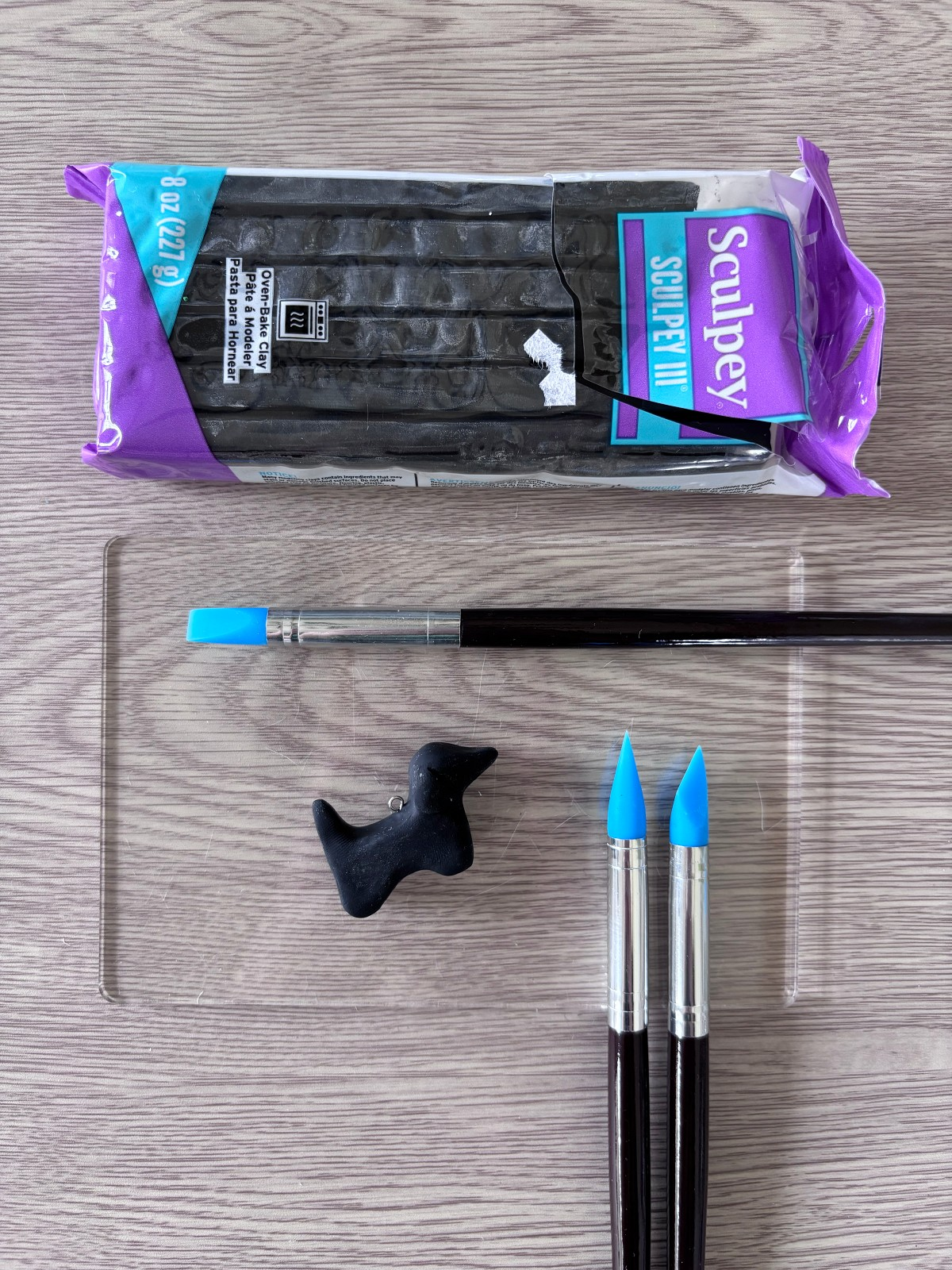 Clay smoothing pen tools next to a clay charm.