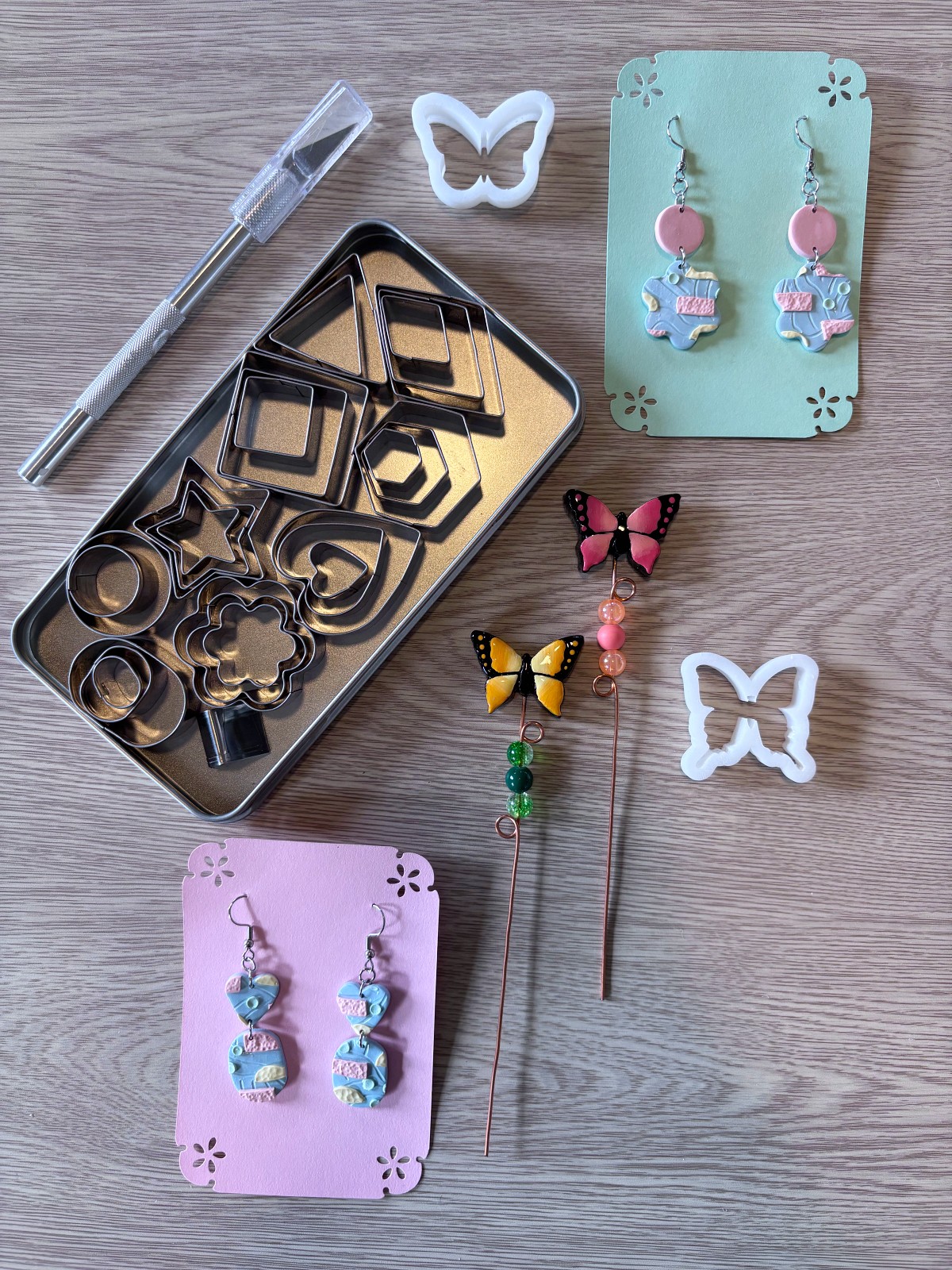 Clay cutter set surrounded by earrings and plant sticks on a table.