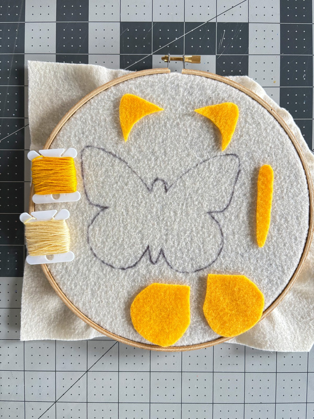 Butterfly ornament pattern pieces, embroidery thread, and embroidery hoop.