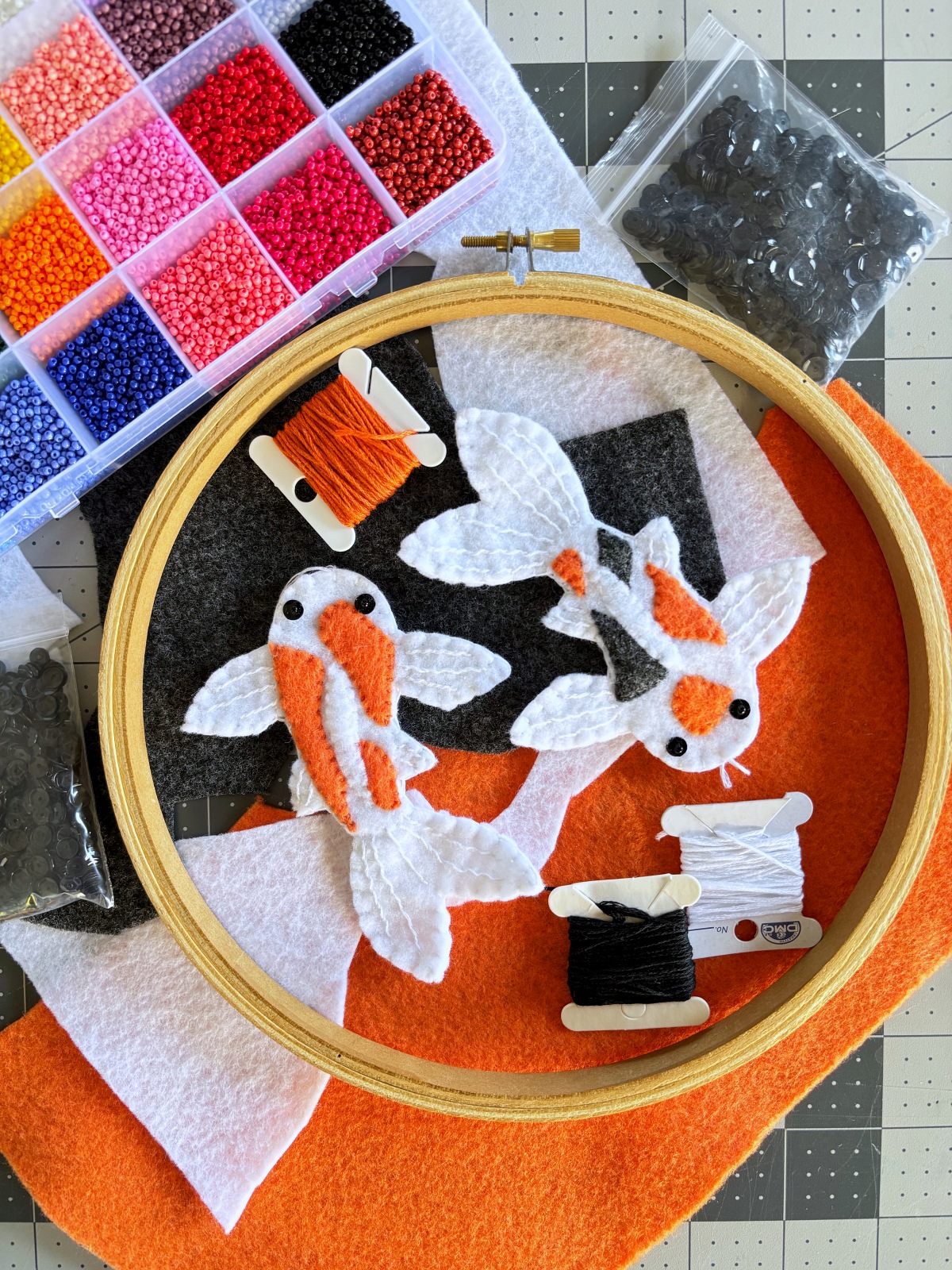 Art supplies surrounding the finished koi fish ornaments.