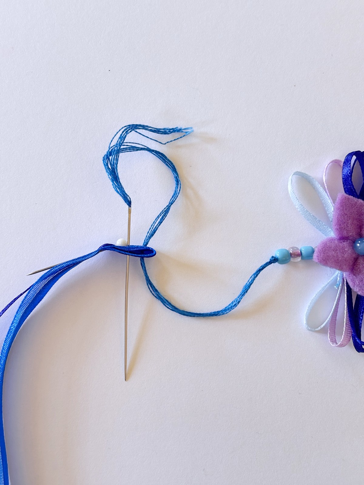 Sewing on the ribbon ties to the flower crown.