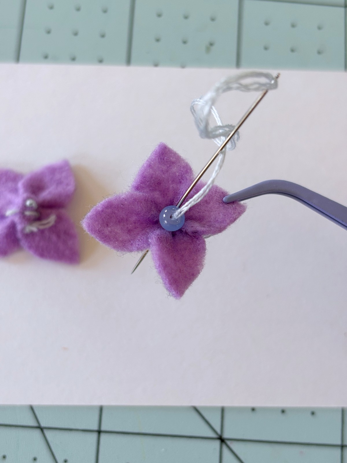 Sewing a bead into the center of the felt flower.