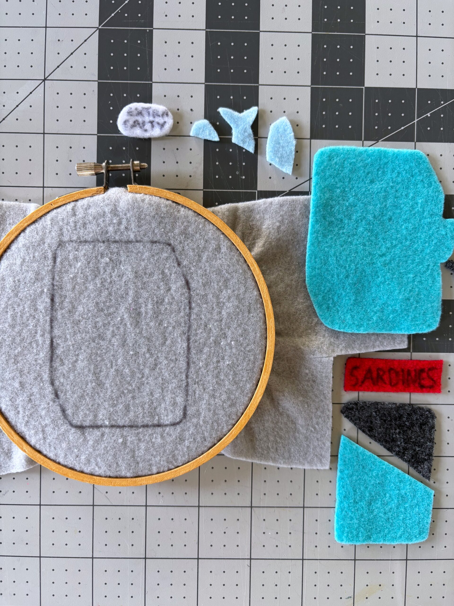 Felt pattern pieces on a table with the base piece in an embroidery hoop.