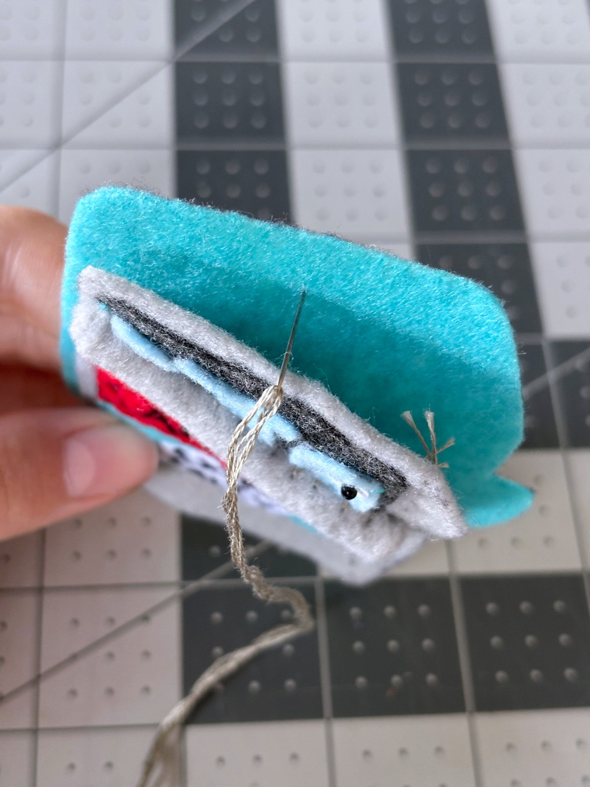 Sewing a blanket stitch starting at the top of the ornament between the two layers of felt.