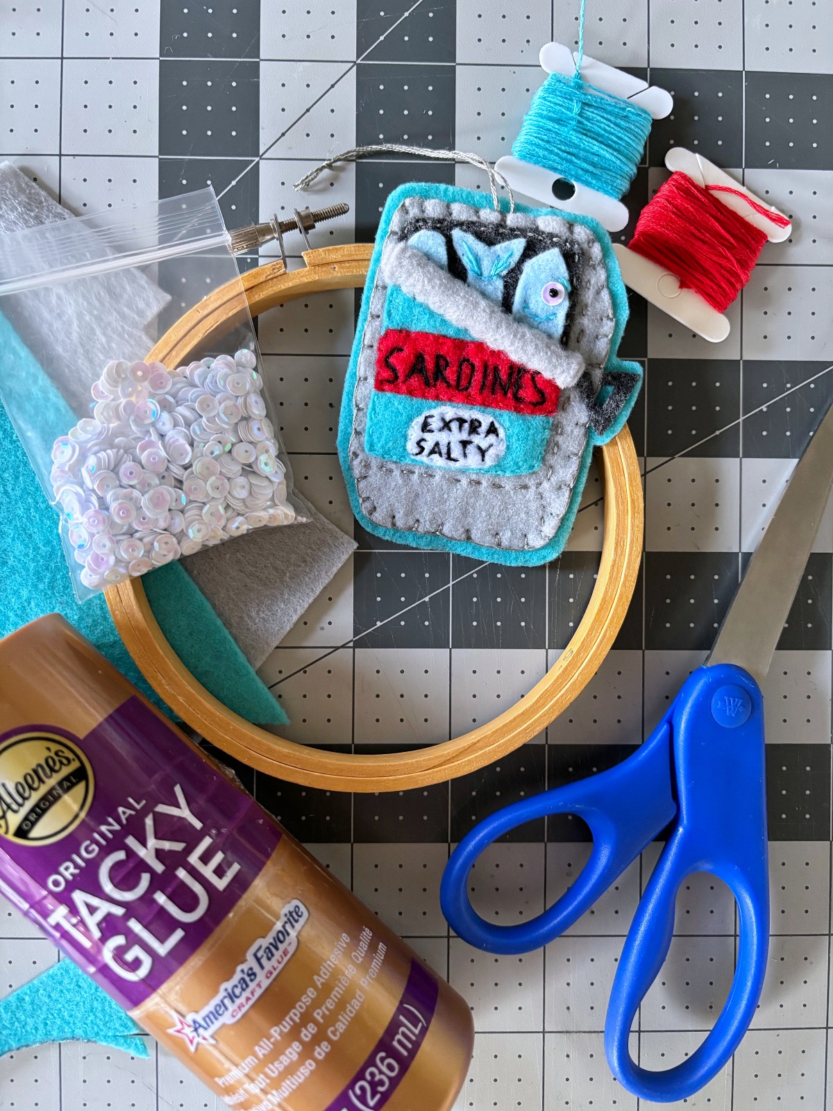 Sardine can felt ornament with sewing materials on a table.