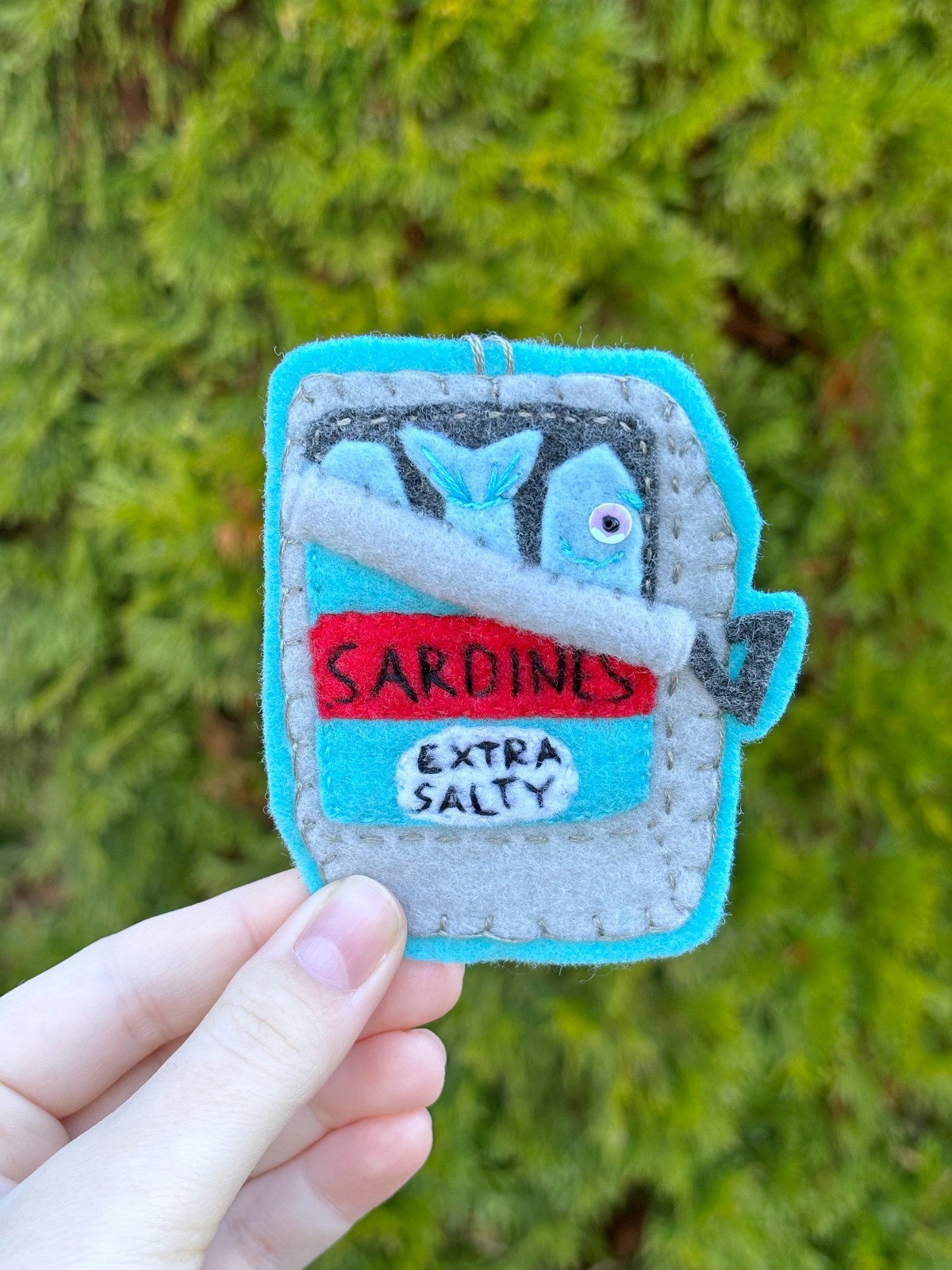 Hand holding finished sardine can ornament outside. 