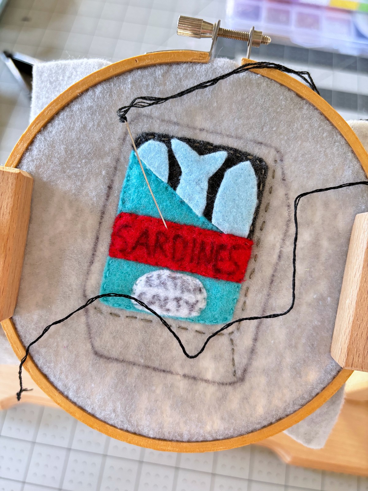 Can label pieces sewn on the base and black embroidery thread on a needle.