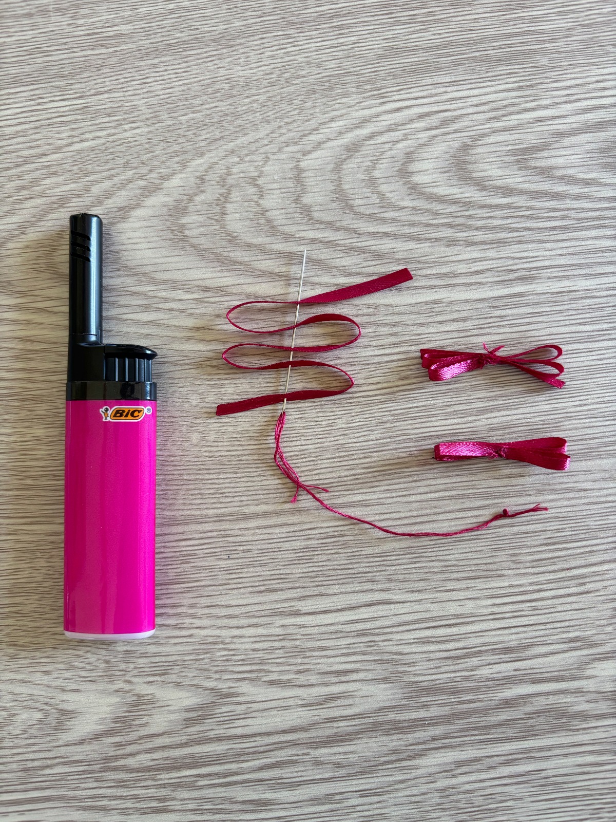 Dark pink ribbon threaded on a sewing needle.