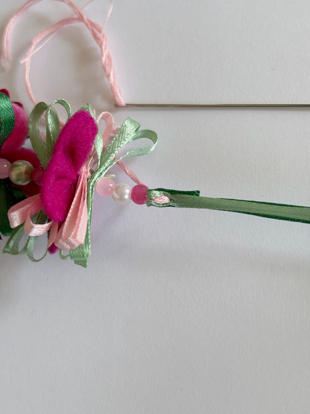 Embroidery thread sewn up and down through the folded ribbon ties.