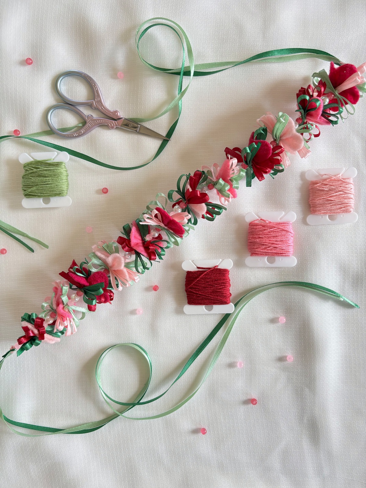 Finished flower crown displayed with scissors, beads, and embroidery thread.