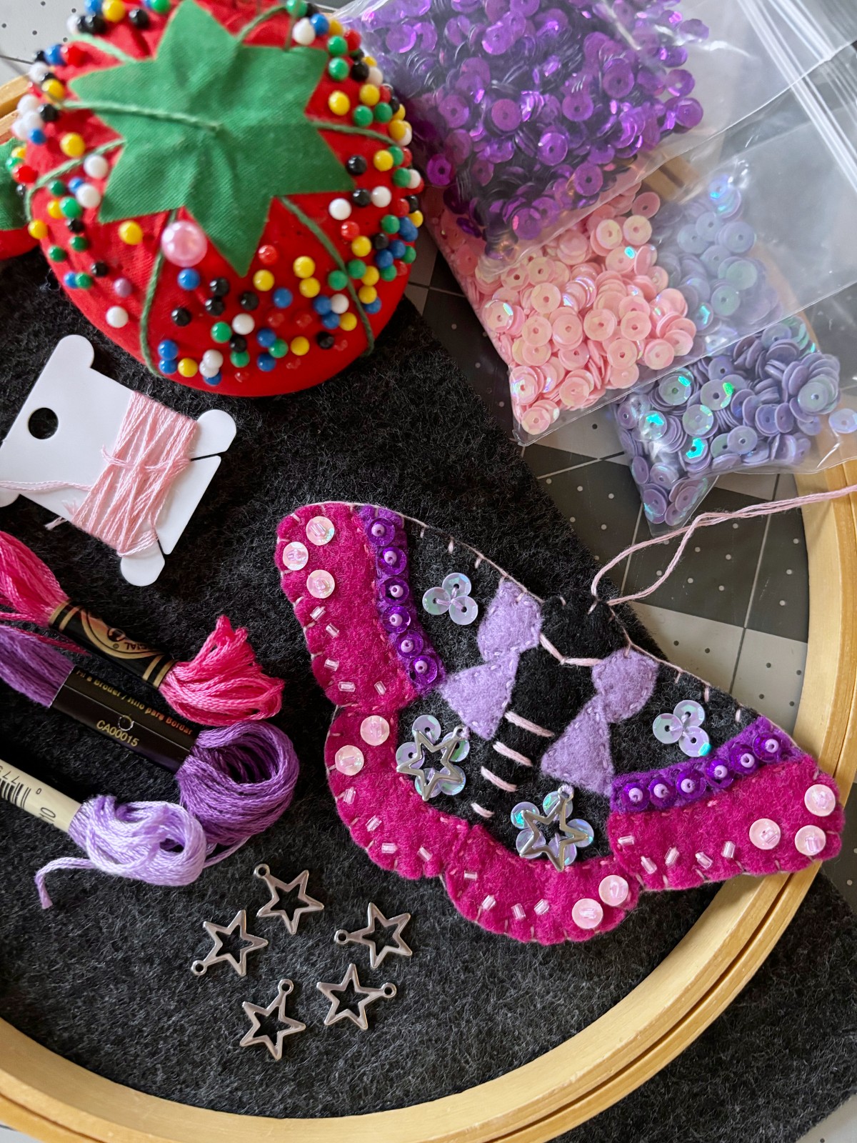 Sewing supplies and moth ornament on a table.