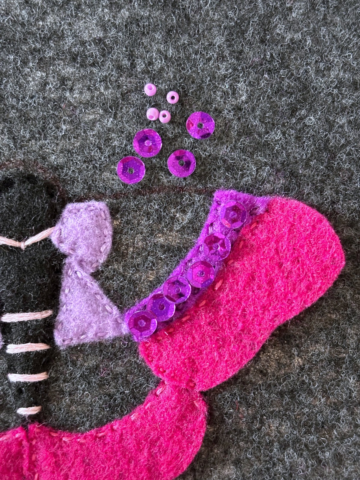 Dark purple sequins arranged on the moths upper wing with seed beads.