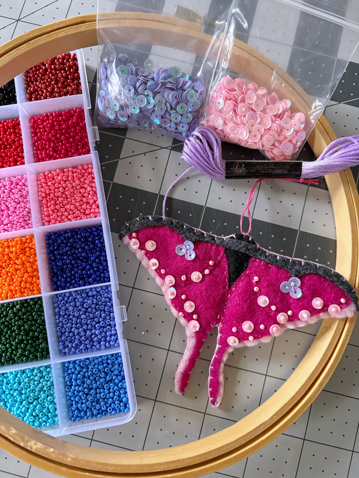 Sewing materials and luna moth ornament on a table.
